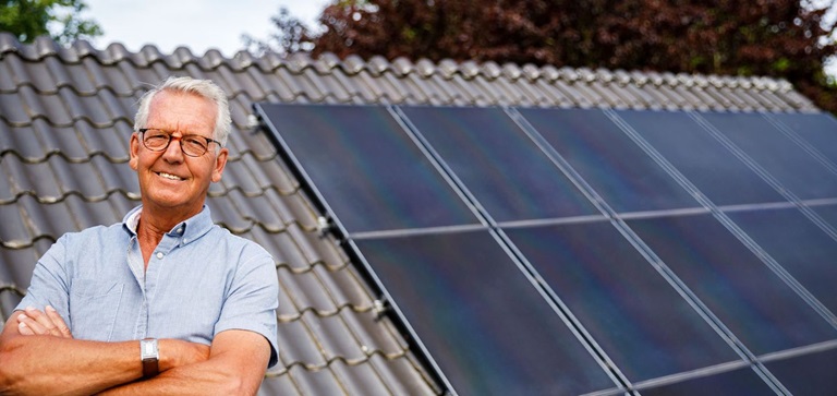 Man naast een dak vol zonnepanelen