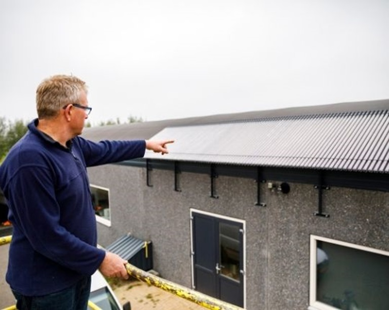 Schapenboer Herman, wijzend naar het dak van zijn stal